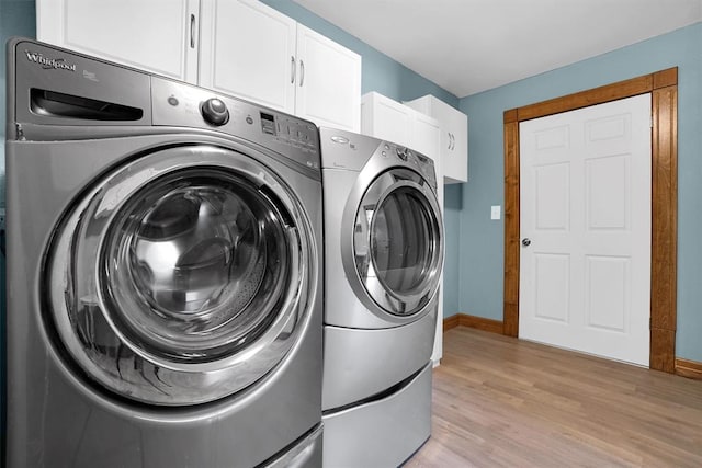 washroom featuring washer and dryer, cabinets, and light wood-type flooring