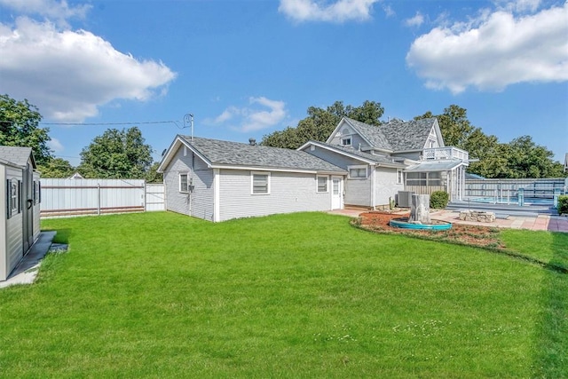 rear view of house with a lawn, central AC, and an outdoor structure