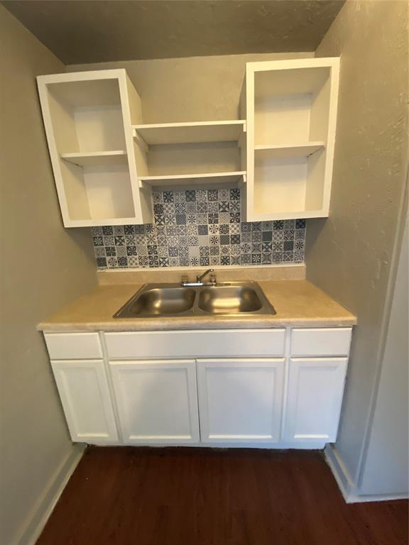 kitchen with decorative backsplash, white cabinetry, sink, and dark hardwood / wood-style floors