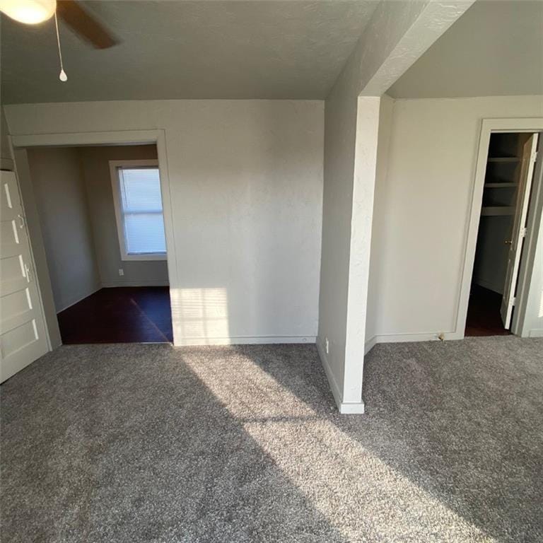 unfurnished room with ceiling fan and dark carpet