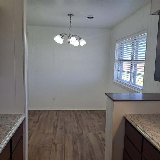 unfurnished dining area with wood-type flooring and an inviting chandelier