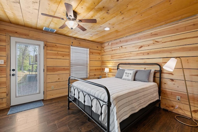 bedroom with ceiling fan, wood ceiling, dark wood-type flooring, and wooden walls