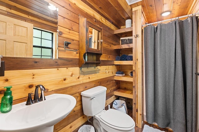 bathroom with curtained shower, sink, wood walls, toilet, and wood ceiling