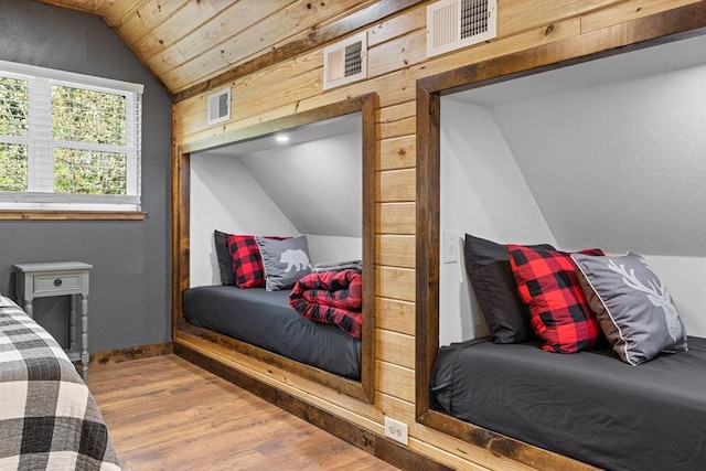 bedroom with wood walls, hardwood / wood-style floors, and lofted ceiling