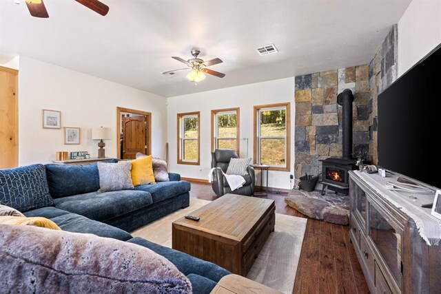 living room featuring hardwood / wood-style flooring, a wood stove, and ceiling fan