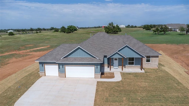 view of front facade with a front yard, a porch, a rural view, and a garage