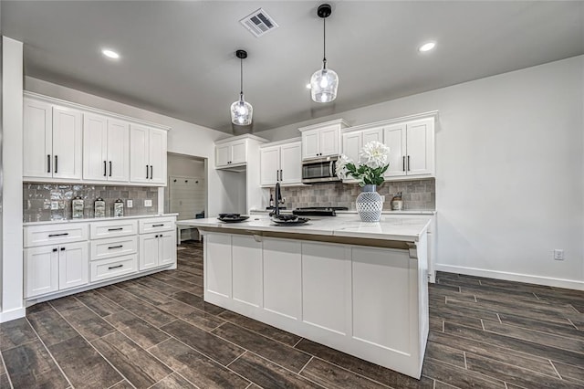 kitchen with backsplash, white cabinetry, an island with sink, and dark wood-type flooring