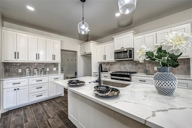 kitchen featuring backsplash, white cabinets, hanging light fixtures, dark hardwood / wood-style floors, and appliances with stainless steel finishes