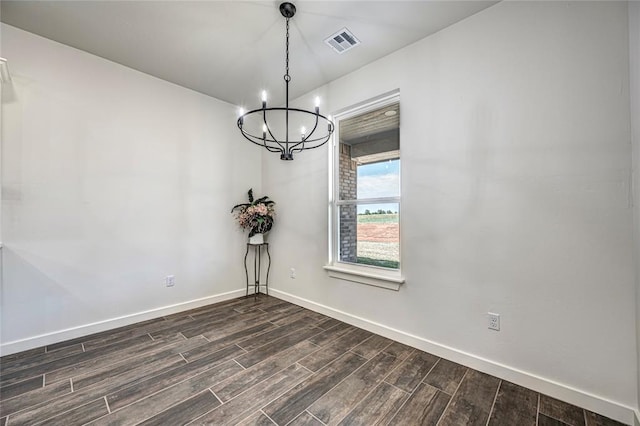 spare room featuring a chandelier and dark wood-type flooring