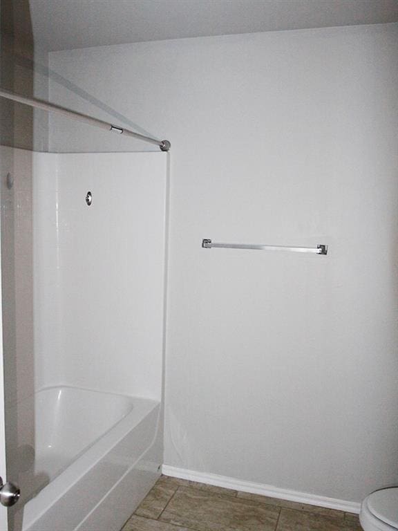 bathroom featuring tile patterned floors, toilet, and washtub / shower combination