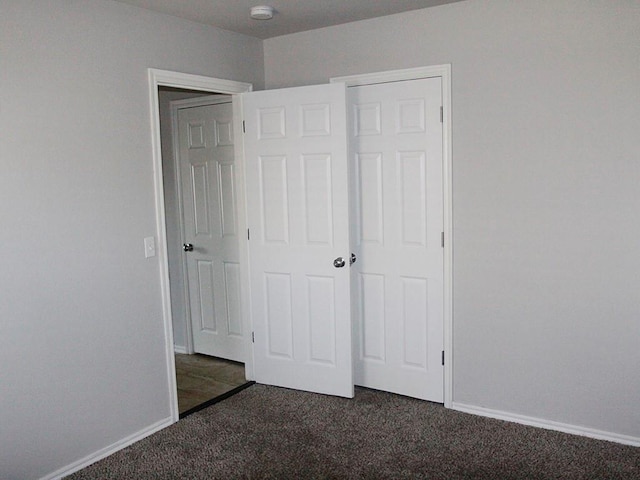 unfurnished bedroom featuring a closet and dark carpet