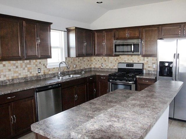 kitchen with tasteful backsplash, stainless steel appliances, sink, a kitchen island, and lofted ceiling