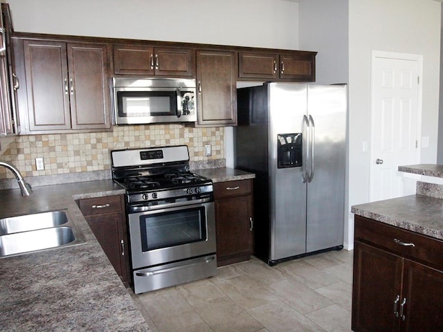 kitchen featuring decorative backsplash, dark brown cabinets, stainless steel appliances, and sink