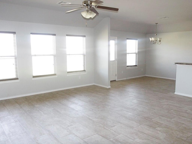 spare room featuring ceiling fan with notable chandelier