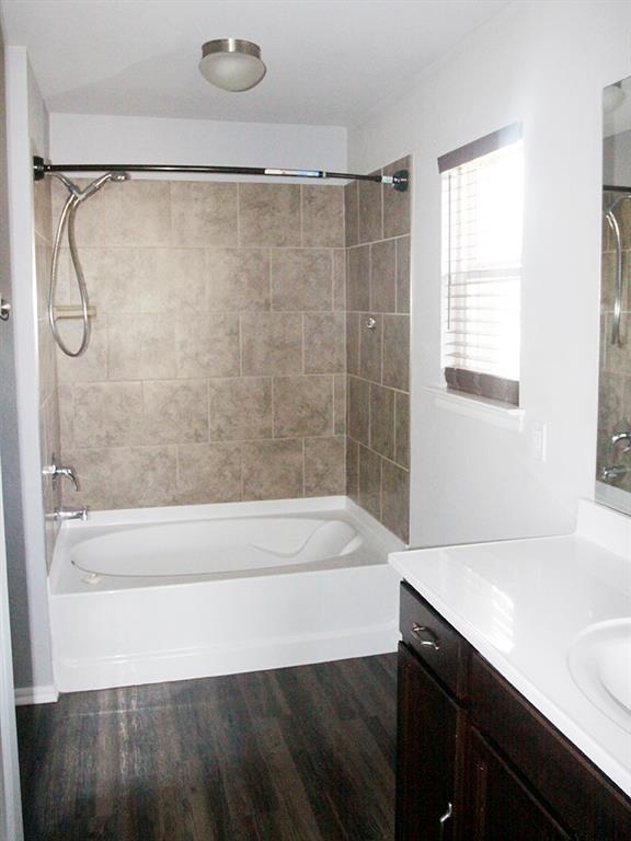 bathroom with hardwood / wood-style floors, vanity, and tiled shower / bath