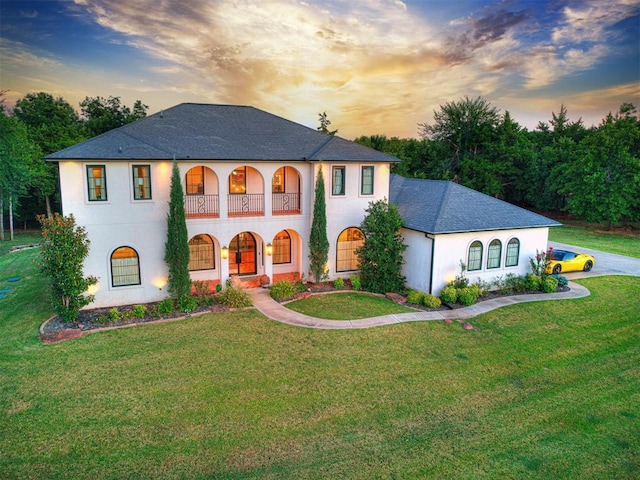 view of front of home featuring a balcony and a yard