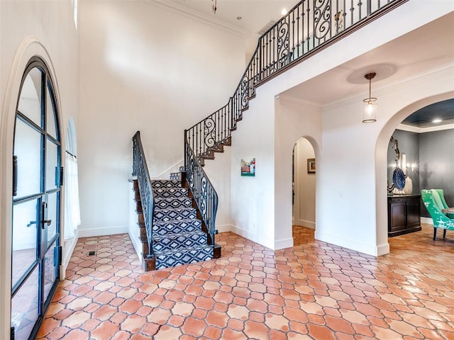 foyer with a towering ceiling and ornamental molding