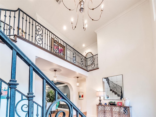 staircase featuring ornamental molding, a towering ceiling, and an inviting chandelier