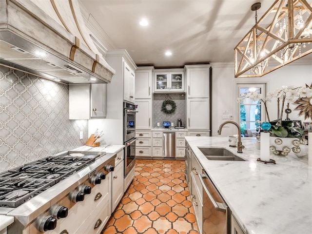 kitchen featuring pendant lighting, white cabinets, sink, appliances with stainless steel finishes, and custom range hood