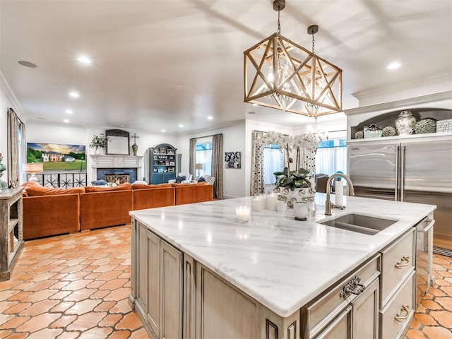 kitchen featuring light stone countertops, decorative light fixtures, a center island with sink, and ornamental molding