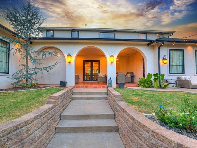 exterior entry at dusk with outdoor lounge area, a yard, and a patio area