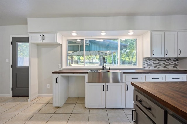 kitchen with white cabinetry, sink, wood counters, tasteful backsplash, and light tile patterned floors