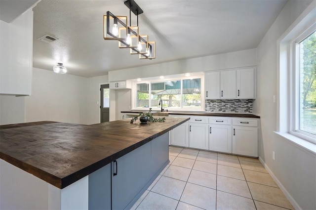 kitchen with decorative backsplash, white cabinetry, pendant lighting, and wooden counters