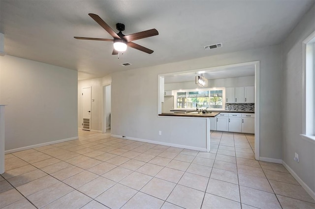 interior space with ceiling fan, white cabinetry, light tile patterned floors, and tasteful backsplash