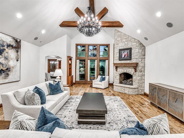 living room with an inviting chandelier, high vaulted ceiling, beamed ceiling, light hardwood / wood-style floors, and a fireplace