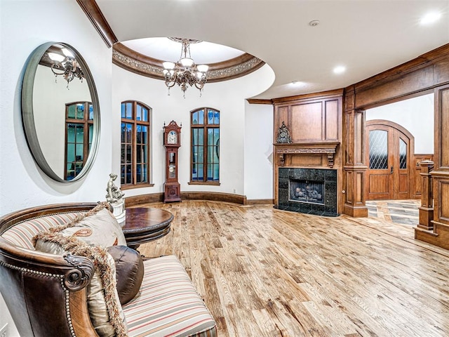 living room featuring hardwood / wood-style floors, crown molding, a fireplace, and an inviting chandelier