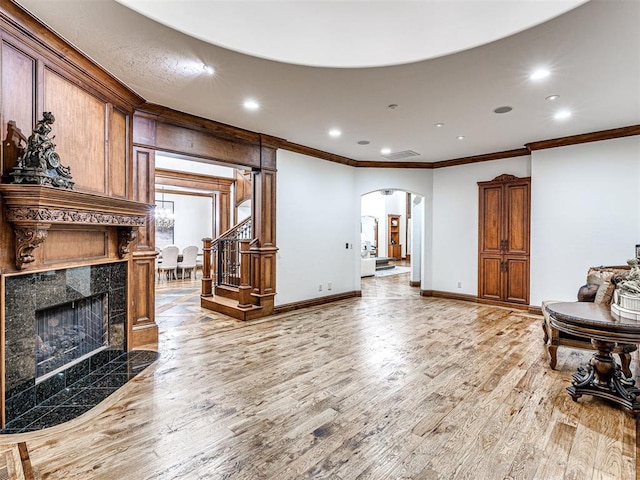 living room with wood-type flooring, crown molding, and a tiled fireplace