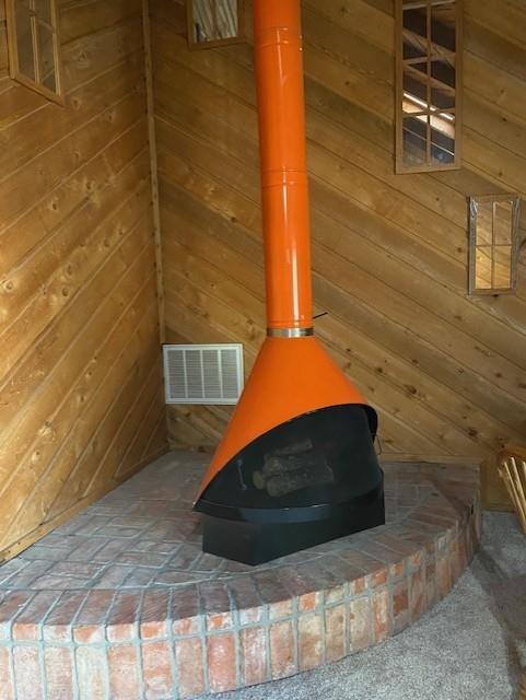 interior details featuring a wood stove and wooden walls