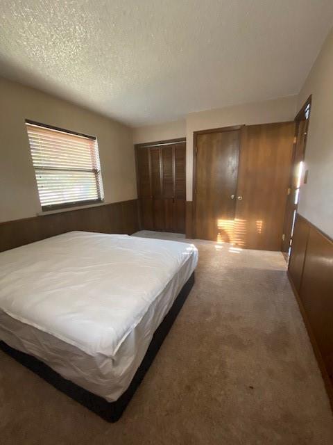 bedroom with carpet flooring, wood walls, and a textured ceiling