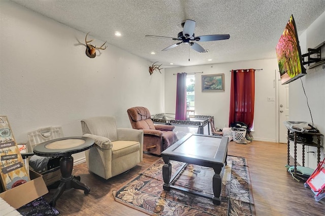 living room with ceiling fan, wood-type flooring, and a textured ceiling