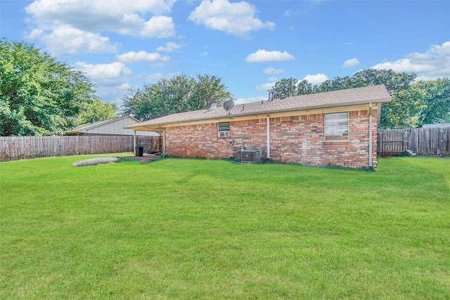 rear view of house with central air condition unit and a yard