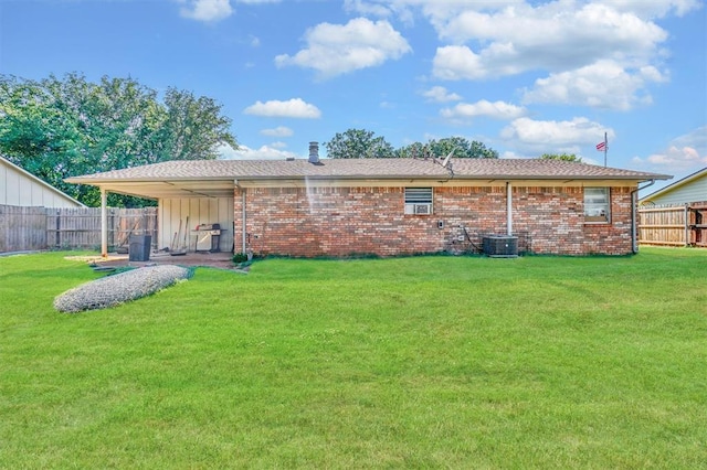 rear view of house with a lawn and central air condition unit