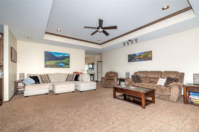 carpeted living room featuring ceiling fan, a raised ceiling, and ornamental molding