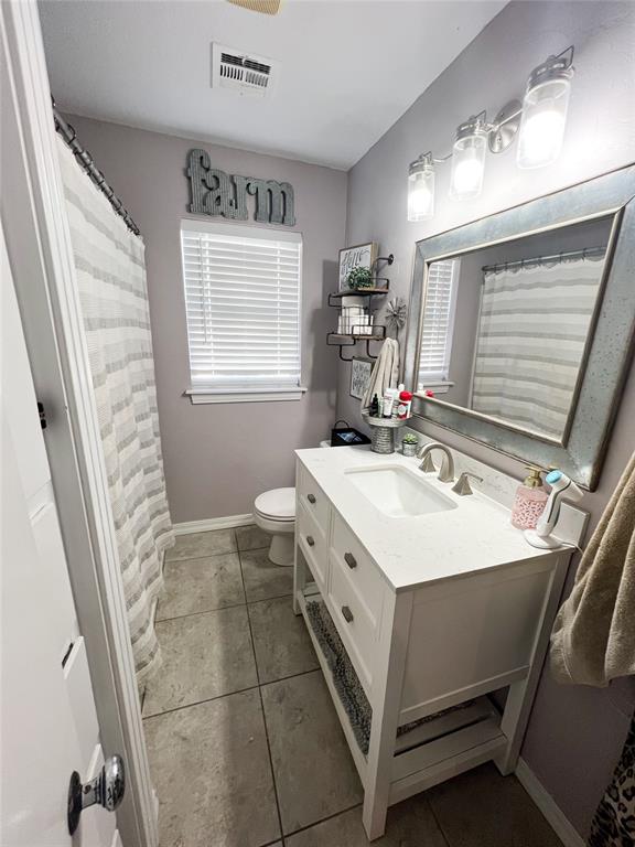 bathroom featuring tile patterned floors, vanity, toilet, and a wealth of natural light