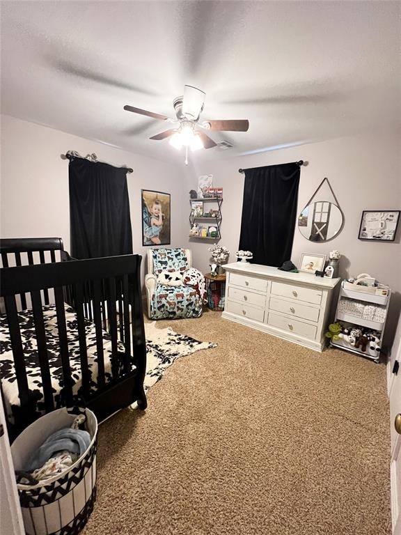 carpeted bedroom with a nursery area and ceiling fan