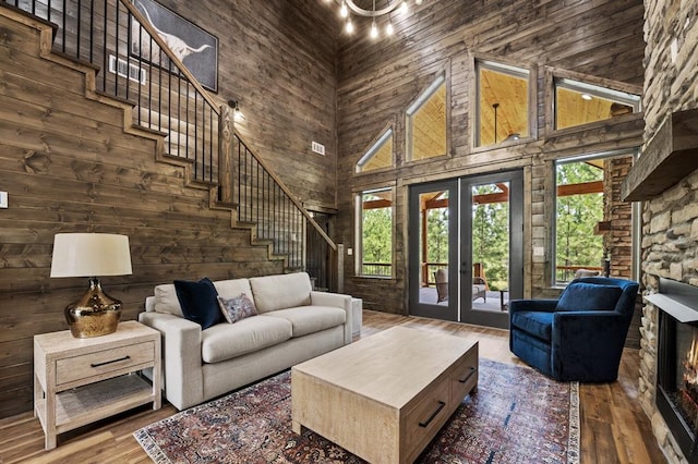 living room featuring hardwood / wood-style floors, a towering ceiling, wooden walls, and french doors