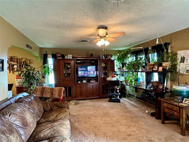 living room with ceiling fan, carpet floors, and a textured ceiling