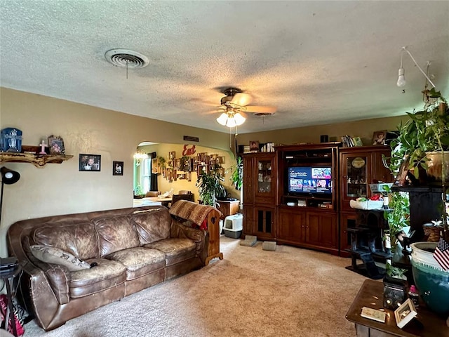 carpeted living room featuring ceiling fan and a textured ceiling