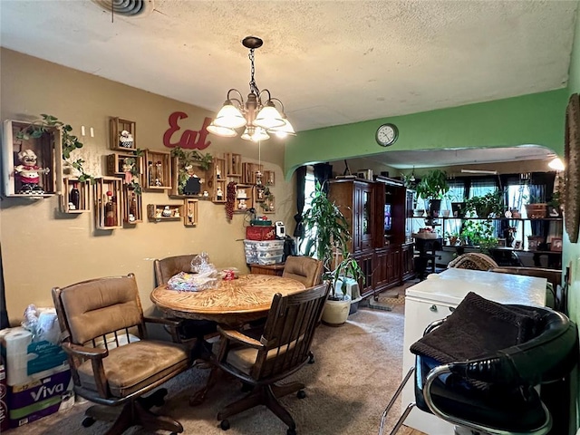 carpeted dining space with a textured ceiling and an inviting chandelier