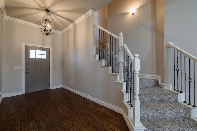 foyer with ornamental molding, dark wood-type flooring, and an inviting chandelier