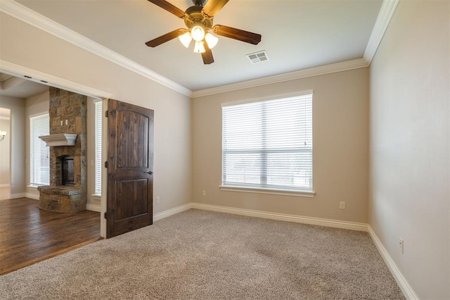 unfurnished room with a fireplace, crown molding, plenty of natural light, and dark colored carpet