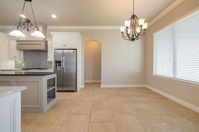 kitchen featuring white cabinetry, hanging light fixtures, stainless steel appliances, backsplash, and ornamental molding