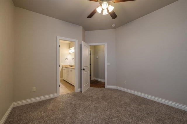 unfurnished bedroom featuring ceiling fan, light colored carpet, and ensuite bath