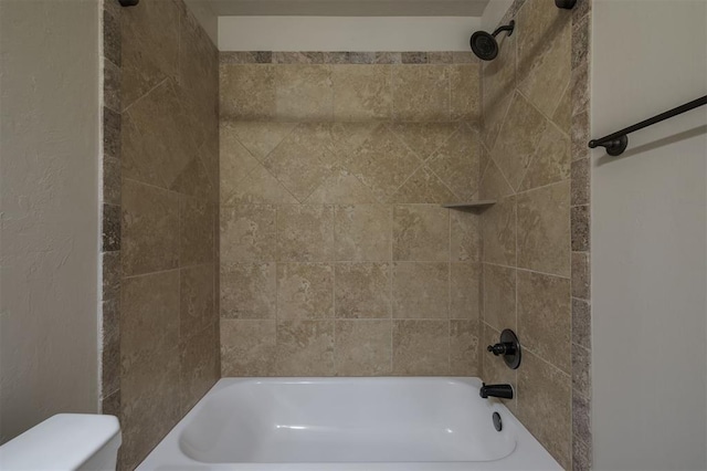 bathroom featuring toilet and tiled shower / bath