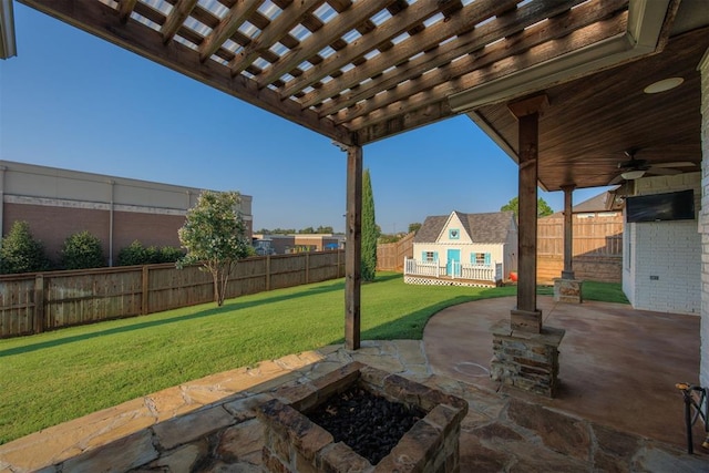 view of patio / terrace featuring ceiling fan, an outbuilding, and an outdoor fire pit