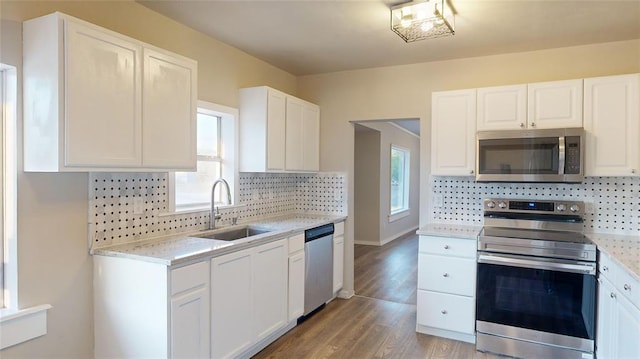 kitchen featuring a wealth of natural light, white cabinetry, sink, and appliances with stainless steel finishes